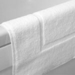 White cotton bath mat placed on hotel bathroom floor – INEQUIP